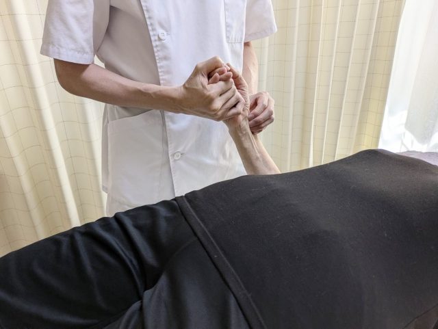 手に鍼の施術を行う写真